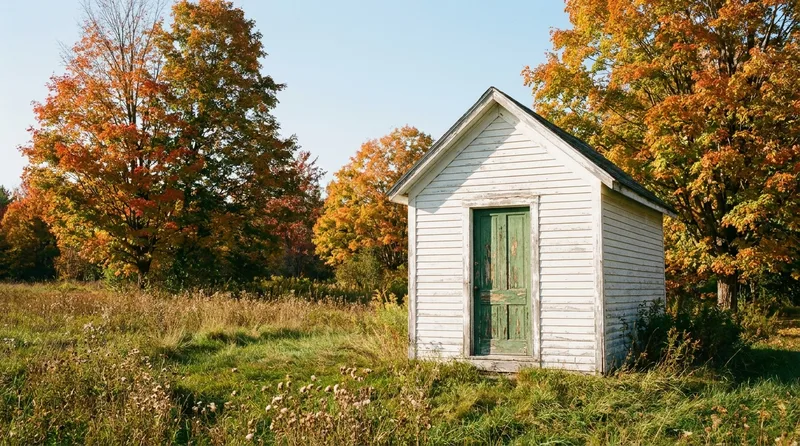 Small New England water pump house beside a wellfield surrounded by autumn trees
