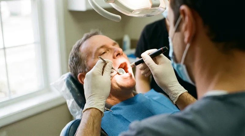 Dentist checking a patient's tongue and throat for signs of sleep apnea