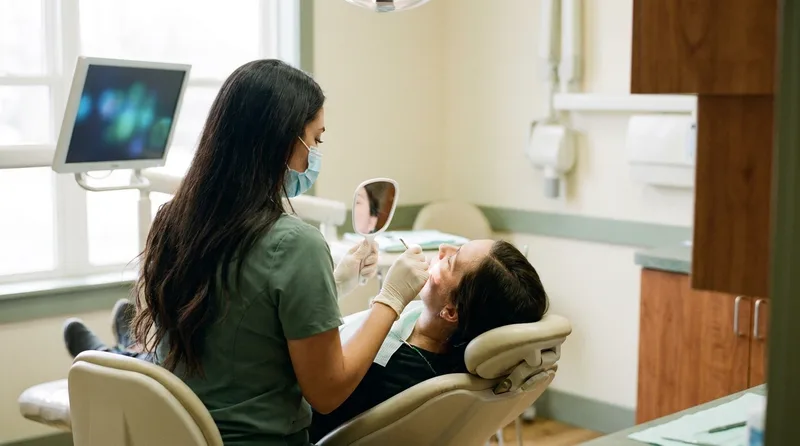 A dentist examining an adult patient's mouth during a routine dental exam